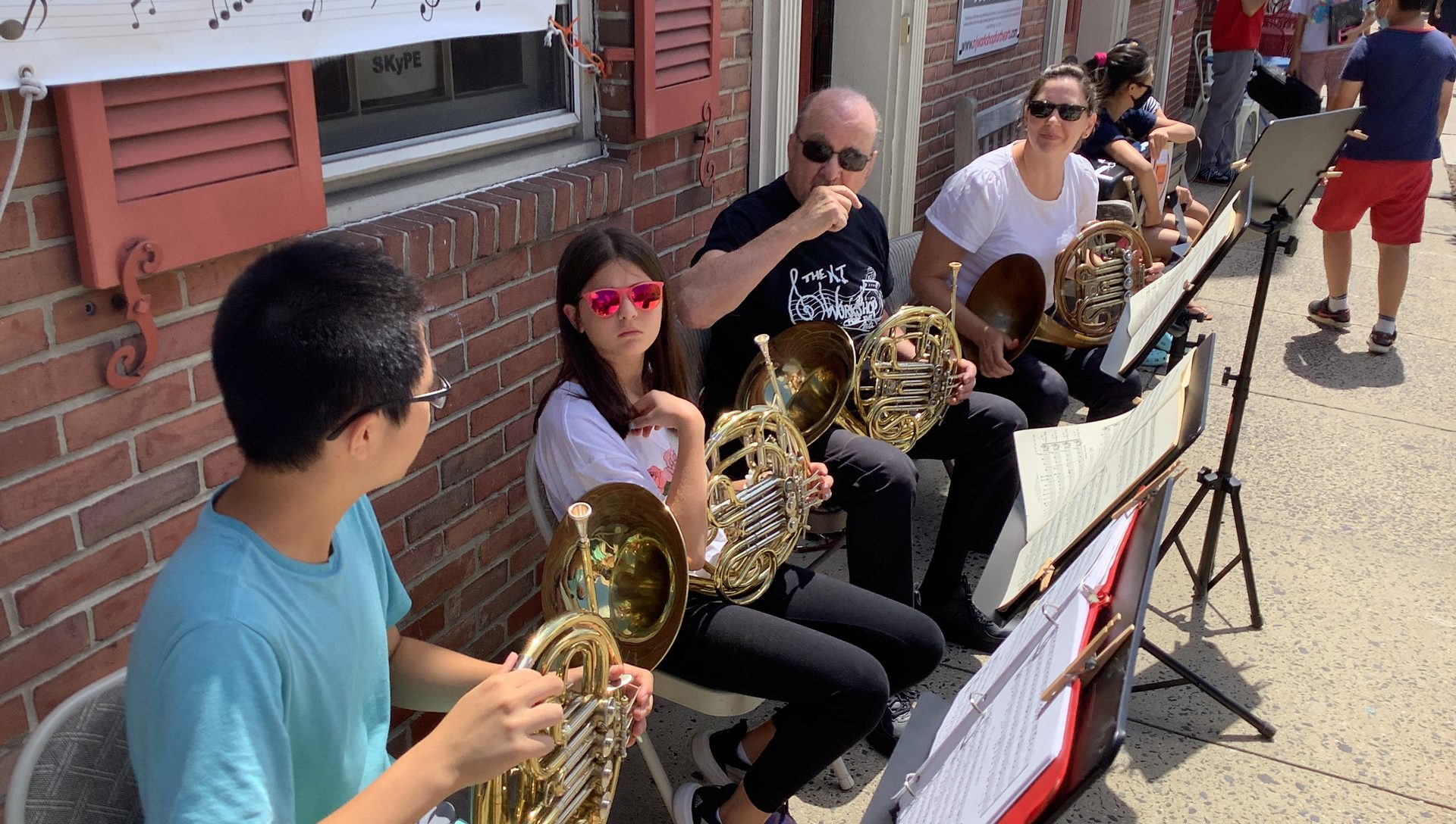 NJWA students playing French horn at an outdoor street performance